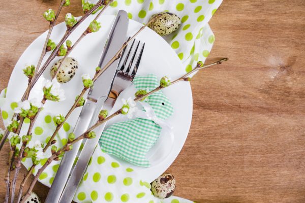 Festive table setting for Easter dinner with spring flowers and cutlery on wooden rustic table. Selective Focus.